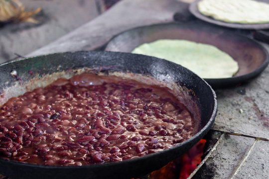 refried beans cooked in a wood stove with background comales