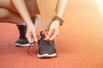 Plakat Close up of runner woman tying shoelaces. Conceptual of woman getting ready for jogging in the running track.