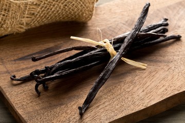 Bundle of tied, dried bourbon vanilla beans or pods on brown wooden cutting board