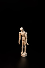 the wooden man Gestalt stands dejectedly and sadly with his head bowed