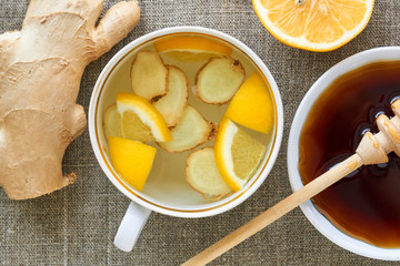 A cup of tea with ginger and lemon on a textile background