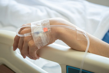 Close up of patient woman hand with receiving intravenous fluid directly into a vein while her hand...
