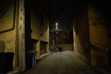 Fototapeta na wymiar Dark and eerie urban city alley at night in the winter