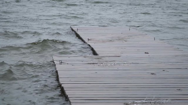 Close up view of lake water playfully jumping out through the wooden deck