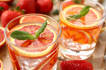 Red orange punch with green mint home made cocktail closeup on wood background