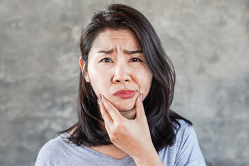depressed Asian woman having problem with Bell's Palsy/Facial Palsy, hand holding her face  - obrazy, fototapety, plakaty