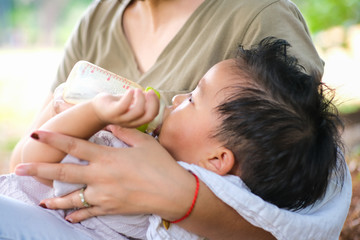 Obraz na płótnie Canvas Toddler baby boy suck breast milk feed by mom in park outdoor