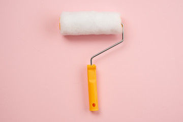 A yellow construction roller lies on a pink background. Tools for repair