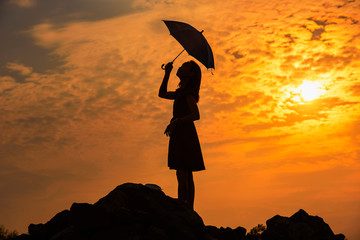 woman holding umbrella with sunset background.