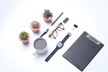 office desk. Workspace with blank clip board, computer keyboard, office supplies, pen, green leaf, eye glassesand,watches, coffee cup on white background.