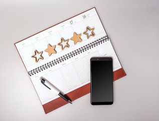 An open notebook in leather binding with a smartphone and pen on a gray background. The concept of...