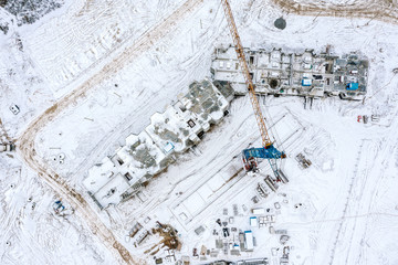 apartment building under construction in winter time. construction site covered with snow. aerial top view