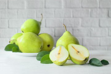 fresh pears in a plate on the table close-up. ripe fresh pears and pear halves on a light background. background with ripe fresh green pears.