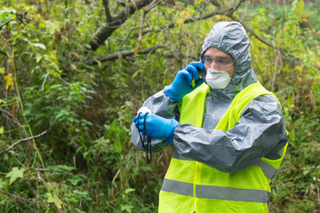 a man in protective gloves and a mask looks at the device showing the level of radiation on the...