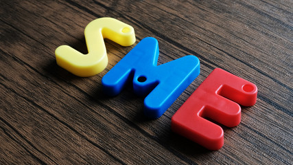 Word 'SME' from wooden letters on dark wooden background