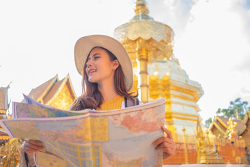 Obraz na płótnie Canvas Smiling woman traveler in doi suthep temple chiangmai landmark in thailand holding world map with backpack on holiday, relaxation concept, travel concept
