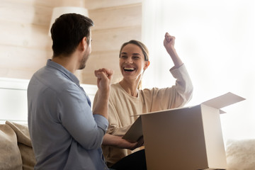 Overjoyed couple smile unpacking online order at home