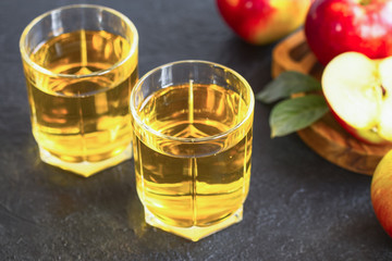 red ripe apples and glasses of apple juice on a dark background. apple juice and apples close-up.