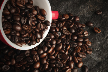 Coffee beans in a cup on a black stone background
