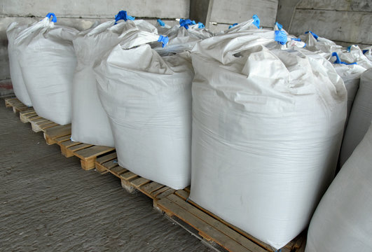 Large bags of grain are stacked in the warehouse.