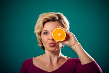 Happy woman holding orange near face. People, lifestyle and health concept