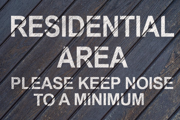 Wall of wooden boards with the inscription RESIDENTIAL AREA PLEASE KEEP NOISE TO A MINIMUM