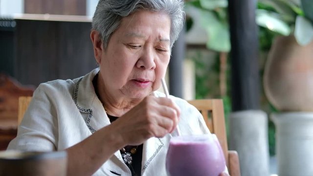 Old Asian Elderly Senior Elder Woman Drinking Berry Smoothie Milkshake At Restaurant. Mature Retirement Lifestyle