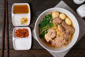 Fine cut white rice noodle in pork soup with meatball and pork in white bowl on wooden table.