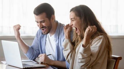 Excited millennial couple triumph reading online news