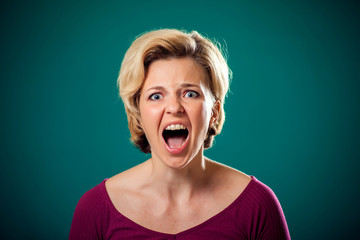 Angry woman in front of green background . People and emotions concept