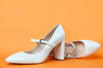 White high heel women's shoes on a orange background. Side view, close up. Stylish trendy shoes for the spring and summer season. Feminine fashion concept. Legendary Mary Jane Shoes.