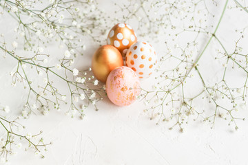 Colorful easter eggs painted in gold, white and pink colors on white background decorated with...