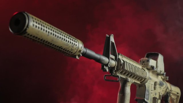 military rifle with a silencer in the smoke