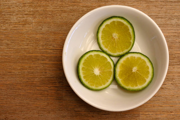 Fototapeta na wymiar Flat lay view of three slices of lime served inside a small white plate