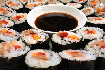 Close up of many sushi slices served on white plate with soy sauce