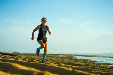 outdoors fitness portrait of young attractive and happy Asian Indonesian woman in compression socks jogging cheerful on the beach doing running workout