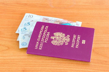 Polish passport with Pound sterling money bill on wooden table.