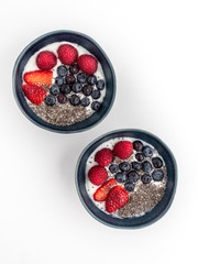 Two blue bowls with yoghurt and fruits. Overhead shot.
