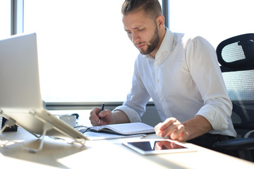 Young modern business man analyzing data using laptop while working in the office.