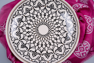 Decorative, painted white with black patterns plate on a kyalagai background.