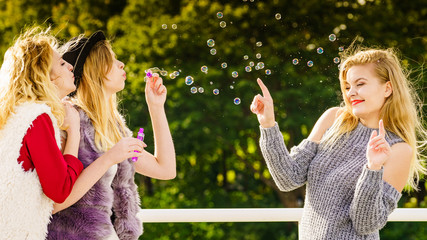 Obraz premium Women blowing soap bubbles, having fun