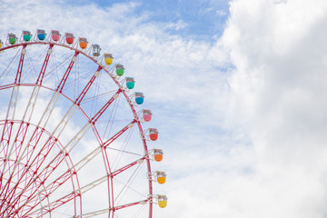 Photograph of a grtan ferris wheel of different colors with a blue sky in the background