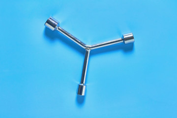 One glossy chrome wrench for nuts lies on blue desk in workshop. Top view. Close-up