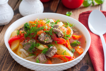 Khashlama with beef and vegetables on a wooden table, selective focus