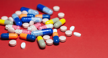 Heap of pills, tablets, capsules on red background. Drug prescription for treatment medication health care concept wth copy space.