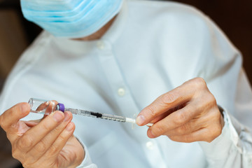 doctor in a white surgical gown  holds in hands a medical syringe and bottle with insulin for...