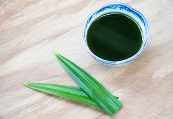 Tiliacora triandra water in a bowl with geen leaf on wood texture.