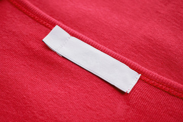 Blank white clothes tag label on new red shirt