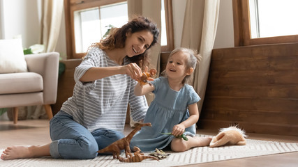 Overjoyed family of two playing with toys on floor carpet.