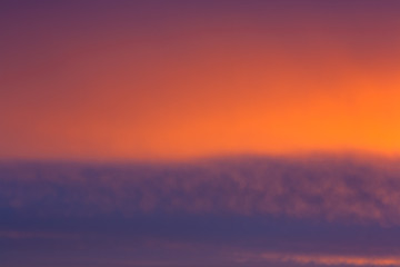 Fiery sunrise clouds in the sky. Early morning sky with colors from deep blue to orange. Sunlight...